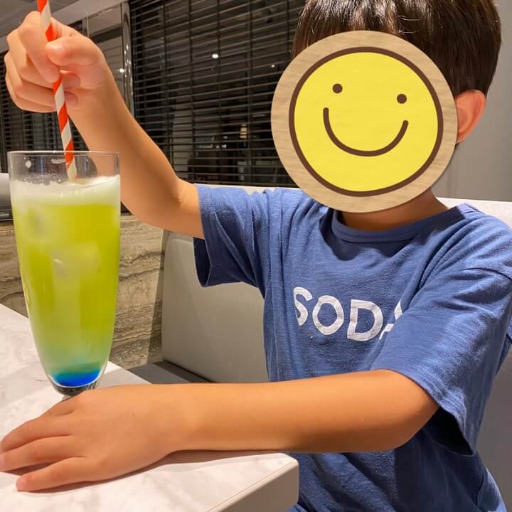  ノンアルコールのブルーシンデレラカクテルを飲む小学生の写真