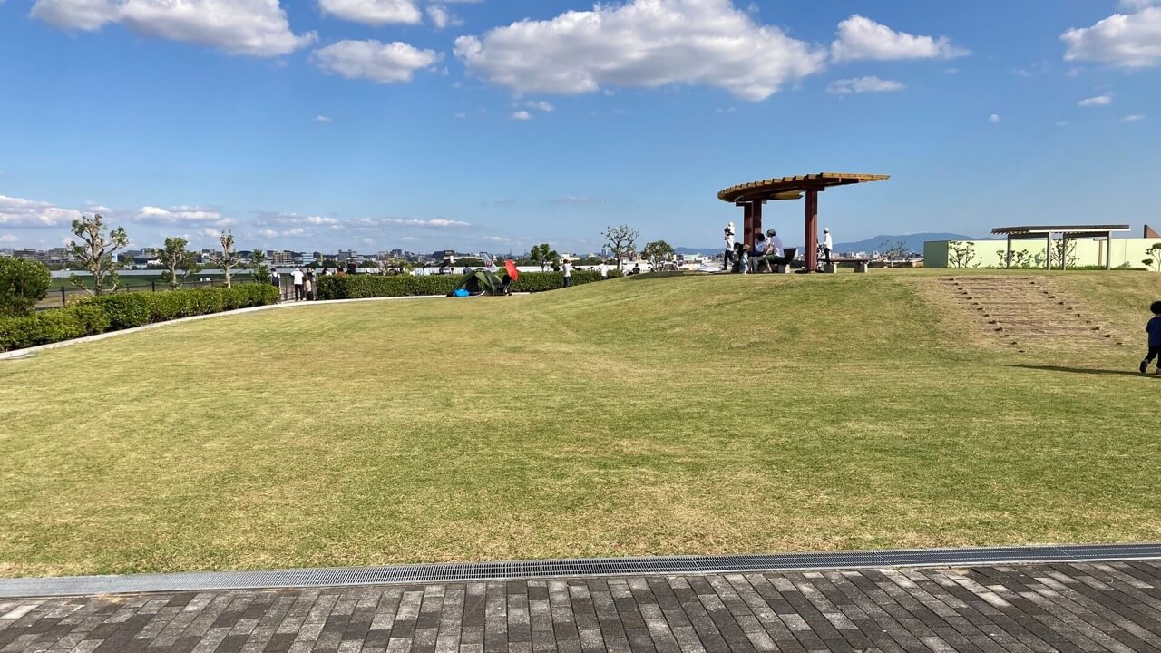 飛行機が見える公園、スカイランドHARADAの芝生広場の写真。奥には伊丹空港の滑走路が見えます。